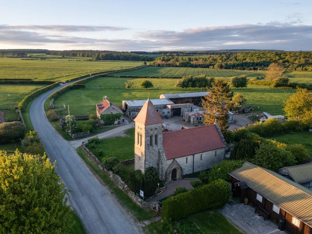 A small church set by a road and surrounded by countryside